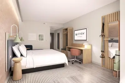 a bedroom with a white bed and a desk with a chair at EVEN Hotel Orlando Universal Blvd by IHG in Orlando
