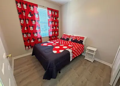a bedroom with a bed with a red and white comforter at Paradise Cay Resort - Close to Disney in Kissimmee