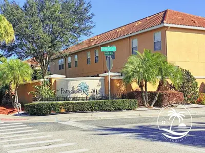 a street sign in front of a building with palm trees at Paradise Cay Resort - Close to Disney in Kissimmee