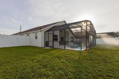 a glass house with a lawn in front of it at Resort-Style Home Near Disney | Pool | Game Room in Kissimmee