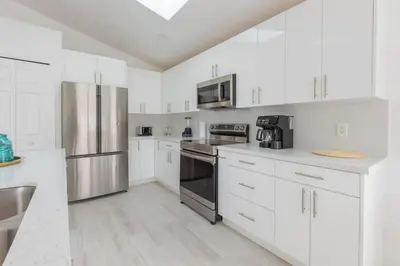 a kitchen with white cabinets and stainless steel appliances at Resort-Style Home Near Disney | Pool | Game Room in Kissimmee
