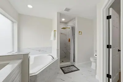 a white bathroom with a tub and a toilet at The Seasons Retreat 5BR Oasis with Private Pool in Kissimmee
