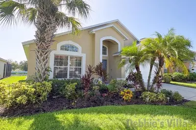 a yellow house with palm trees in a yard at Seasons Kissimmee in Kissimmee