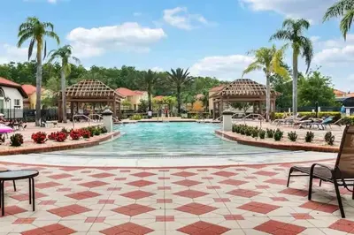 a pool at a resort with chairs and palm trees at Stylish 4BR Townhome Private Pool BBQ & Near Disney in Kissimmee