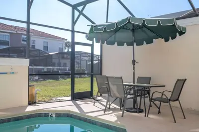 a patio with a table and chairs and an umbrella at Stylish 4BR Townhome Private Pool BBQ & Near Disney in Kissimmee