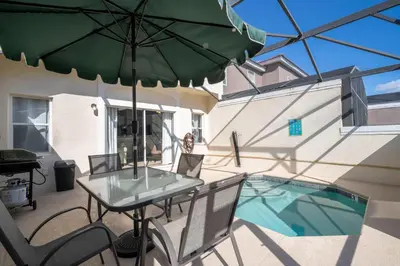a patio with a table and a green umbrella at Stylish 4BR Townhome Private Pool BBQ & Near Disney in Kissimmee