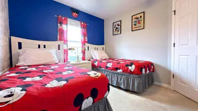a bedroom with two beds with mickey mouse sheets at Stylish 4BR Townhome Private Pool BBQ & Near Disney in Kissimmee