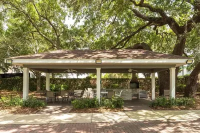 a pavilion with tables and chairs under a tree at Casa 4Q Moderna em Lucaya Village Kissimmee in Kissimmee