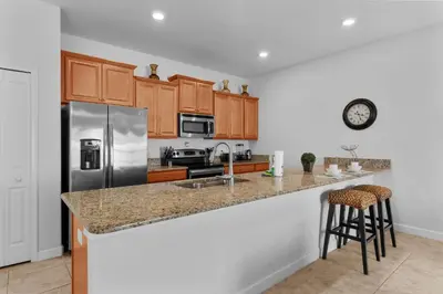a kitchen with wooden cabinets and a stainless steel refrigerator at Townhome 4Q Storey Lake - 10 min Disney in Kissimmee