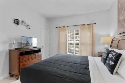 a bedroom with a bed and a dresser and a television at Townhome 4Q Storey Lake - 10 min Disney in Kissimmee