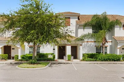 a large white building with a tree in a parking lot at Townhome 4Q Storey Lake - 10 min Disney in Kissimmee