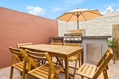 a wooden table and chairs with an umbrella and a grill at 5 Suites Sleeps 14 Lion King Mickey Theme in Orlando