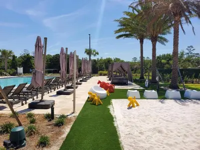 a resort with chairs and a pool with palm trees at 4BR Disney Area Townhome - Pool, Grill & Clubhouse in Orlando