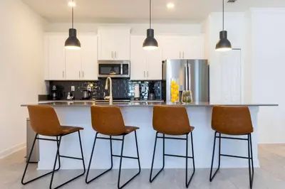 a kitchen with a counter with four chairs at it at Townhome 4Q Storey Lake - Piscina & Temas in Kissimmee