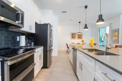 a kitchen with white cabinets and a black refrigerator at Townhome 4Q Storey Lake - Piscina & Temas in Kissimmee