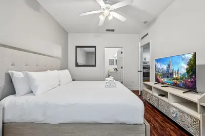 a bedroom with a white bed and a flat screen tv at Near Disney! Kissimmee Home for 12 w/ Pool Access! in Kissimmee