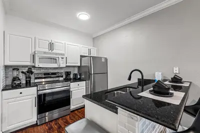 a kitchen with white cabinets and a black counter top at Near Disney! Kissimmee Home for 12 w/ Pool Access! in Kissimmee