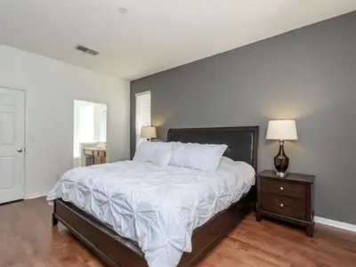 a bedroom with a bed with white sheets and a wooden floor at Holiday Home 2696LIC by Interhome in Kissimmee
