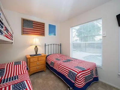 two beds in a bedroom with an american flag on the wall at Holiday Home Ausgezeichnetes Preis-Leistungs-Verhältnis Familienvilla - Süd-West Privater Po by Interhome in Kissimmee