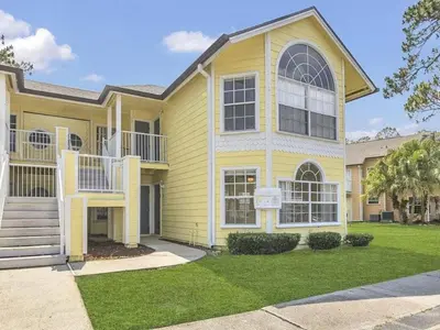a large yellow house with a porch at Apartment 3-Bett-Eigentumswohnung Familienspaß in der Nähe von Disney by Interhome in Kissimmee