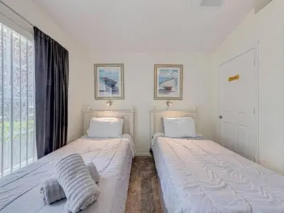 two beds in a room with a window at Holiday Home 3-Schlafzimmer Value Plus Haus mit privatem Pool by Interhome in Kissimmee