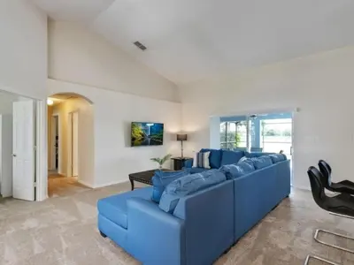 a living room with a blue couch and a table at Holiday Home Entspannende Familienvilla mit privatem Pool und Spa- Große Lanai mit reichlich by Interhome in Orlando