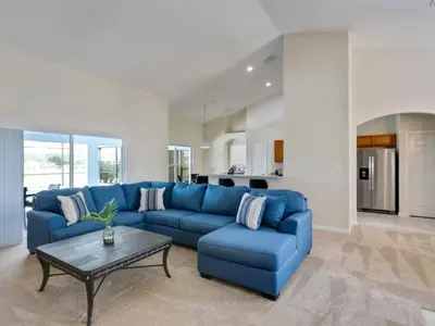 a living room with a blue couch and a table at Holiday Home Entspannende Familienvilla mit privatem Pool und Spa- Große Lanai mit reichlich by Interhome in Orlando