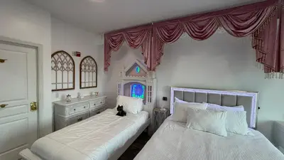 a bedroom with two beds and a cat sitting on the bed at Disney Princess and Heroes Apartment Accessible in Orlando