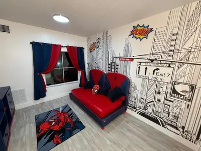 a living room with a red chair and a superhero mural at Disney Princess and Heroes Apartment Accessible in Orlando