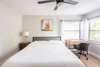 a bedroom with a bed and a desk and a ceiling fan at The Pineapple Express in Orlando