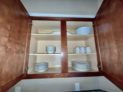a cabinet filled with plates and bowls on shelves at Entire Condo 3Bed 2Bath 5 mins to Disney Park in Orlando