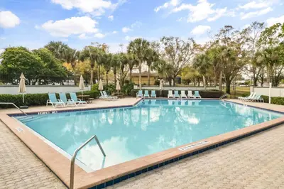 a large swimming pool with lounge chairs and trees at Residentas Hali Ridge in Orlando