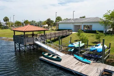a dock with three canoes on the water next to a house at Mario & Fairy 3BR Condo w Free Water Park 303 in Kissimmee