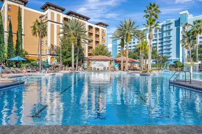 a large swimming pool with palm trees and buildings at Free Breakfast & Parking 2B Disney Resort Condo in Orlando