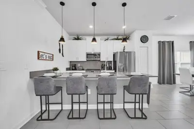 a kitchen with a island with chairs and a counter top at Luxury, Luxury, Luxury Pool Home! townhouse in Kissimmee