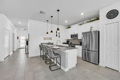 a white kitchen with a counter and a refrigerator at Luxury, Luxury, Luxury Pool Home! townhouse in Kissimmee