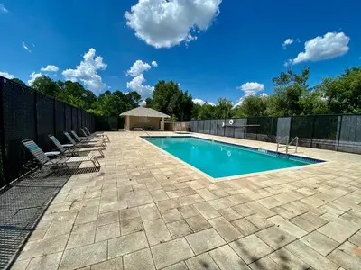 a swimming pool with chairs and a fence at Superior 3BR Condo Apartment Near Disney Attractions in Kissimmee