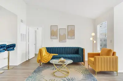 a living room with a blue couch and a yellow chair at Grand Luxury 2BR Penthouse near Disney Parks in Kissimmee