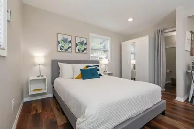a bedroom with a large white bed with blue pillows at Bungalow near Universal, Disney, and Downtown Orlando in Orlando
