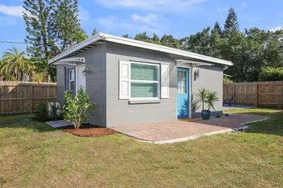 a small house with a blue door in a yard at Bungalow near Universal, Disney, and Downtown Orlando in Orlando