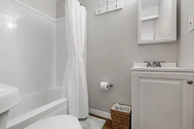 a white bathroom with a shower and a sink at Bungalow near Universal, Disney, and Downtown Orlando in Orlando