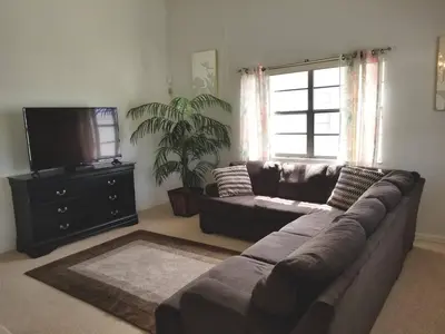 a living room with a couch and a flat screen tv at 4 Bedroom Private Pool House - 5 Mi to Convention Center & 7 Mi to Disney in Orlando