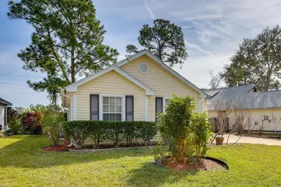 a white house with a tree in the yard at Bright Lakefront Sanford Home with Community Pool in Sanford