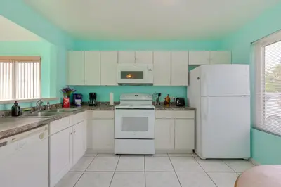 a kitchen with white appliances and blue walls at Bright Lakefront Sanford Home with Community Pool in Sanford