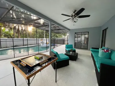 a living room with a ceiling fan and a pool at Beautiful pool home 15 minutes from Disney! in Kissimmee