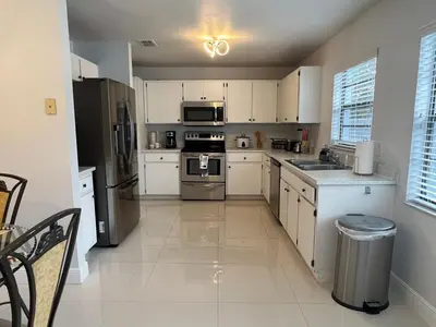 a kitchen with white cabinets and stainless steel appliances at Beautiful pool home 15 minutes from Disney! in Kissimmee