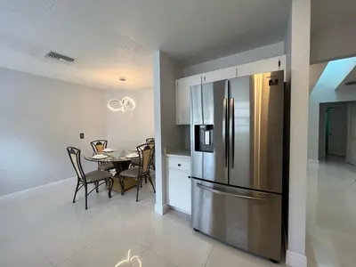 a kitchen and dining room with a stainless steel refrigerator at Beautiful pool home 15 minutes from Disney! in Kissimmee