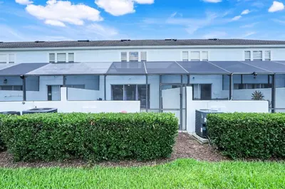 a white building with bushes in front of it at Disney Min Away - Pool Patio & BBQ in Orlando
