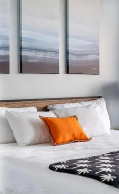 a bed with white pillows and an orange pillow at Blue Heron Resort in Orlando