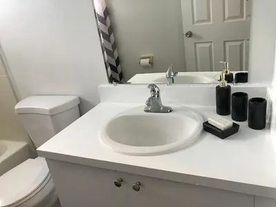 a white bathroom with a sink and a toilet at 10 minutes to all Disney parks with pool and wifi in Kissimmee